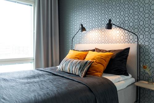 Un dormitorio con una cama con almohadas naranjas y una ventana. en Vasko luxurious suites, Hilla, en Rovaniemi