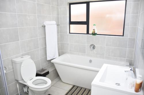 a white bathroom with a toilet and a sink at The Blyde in Pretoria