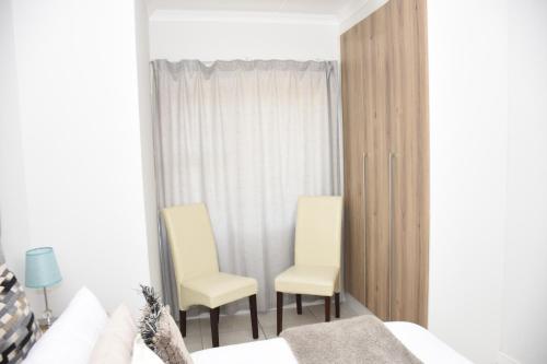 a bedroom with two chairs and a bed at The Blyde in Pretoria