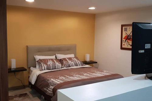 sypialnia z łóżkiem i telewizorem z płaskim ekranem w obiekcie Apartamento Parque Virrey w mieście Bogota