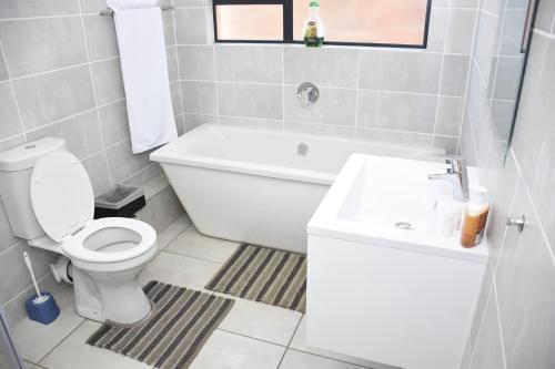 a bathroom with a toilet and a tub and a sink at The Blyde - Beachfront in Pretoria