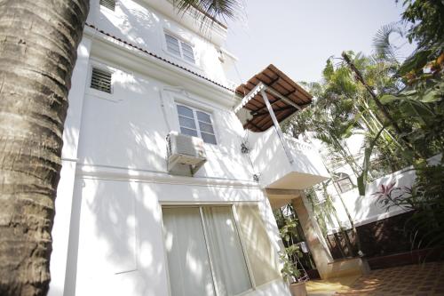a white house with a door and a palm tree at Victoria Villa in Sinquerim