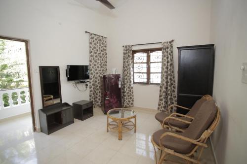 uma sala de estar com duas cadeiras e uma televisão em Victoria Villa em Sinquerim