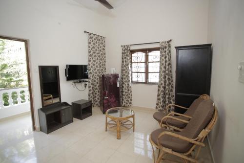 a living room with two chairs and a tv at Victoria Villa in Sinquerim
