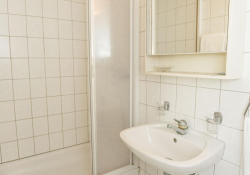 a white bathroom with a sink and a shower at Speiserestaurant Traube in Küttigen