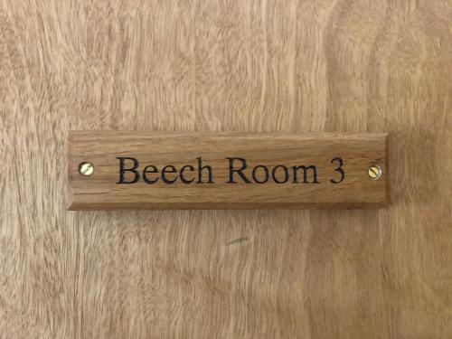 a wooden sign on a door with the words beach room three at The Fossil Tree Hotel in Blackpool