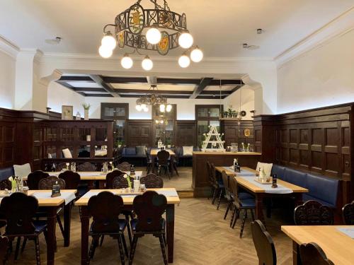 a restaurant with tables and chairs and a chandelier at Münchner Hofbräu Coburg in Coburg