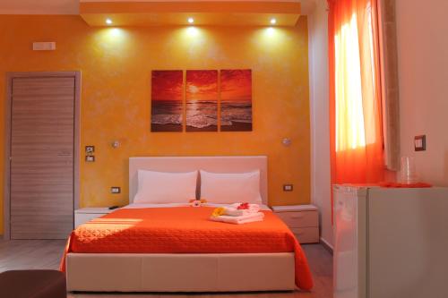 1 dormitorio con 1 cama con colcha de color naranja en B&B Lizia, en Porto Cesareo