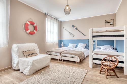 a bedroom with two bunk beds and a chair at Maison Les Burons in Le Bois-Plage-en-Ré