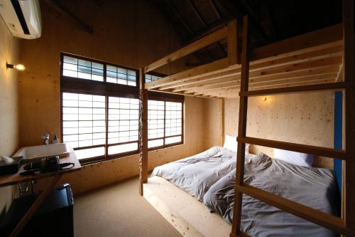 a bedroom with a bunk bed and a desk and window at まちの別邸 緝 shu in Kochi