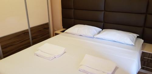 a bed with two white pillows and a black headboard at Monte Liza in Dobra Voda