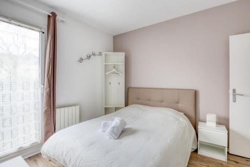 ein weißes Schlafzimmer mit einem Bett und einem Fenster in der Unterkunft Le Petit Magny in Magny-le-Hongre