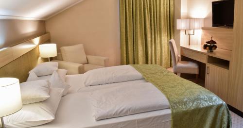 a hotel room with a white bed and a chair at Hotel Park in Široki Brijeg