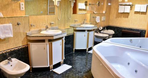 a bathroom with two sinks and a tub and two toilets at Hotel Park in Široki Brijeg