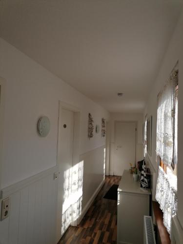 a kitchen with white walls and wooden floors and windows at Pension Mien Fründt in Baabe