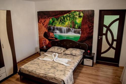 a bedroom with a bed with a waterfall mural on the wall at Casa Robi in Peştişani