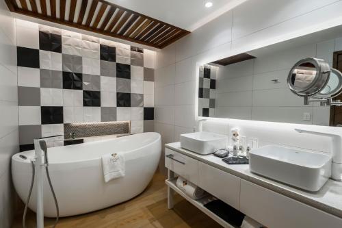 a bathroom with a tub and two sinks and a mirror at FCH Hotel Providencia in Guadalajara