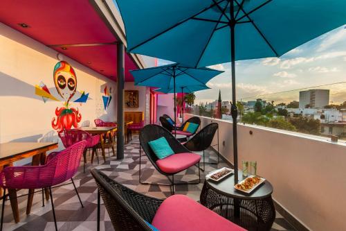 a rooftop patio with chairs and tables and umbrellas at FCH Hotel Providencia in Guadalajara