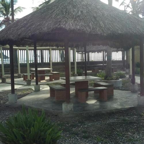 a pavilion with tables and a straw roof at Costa Grande Tucacas Morrocoy in Tucacas