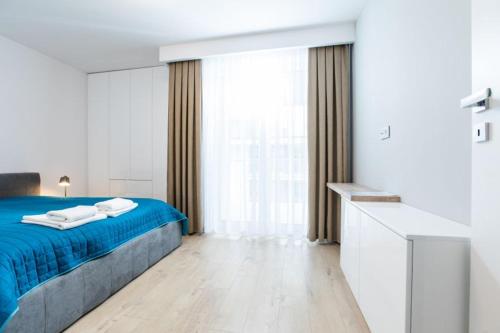 a bedroom with a blue bed and a large window at Resort Apartamenty Klifowa Rewal 30 in Rewal