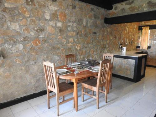 a wooden table with chairs and a stone wall at Madrugada in Umtali