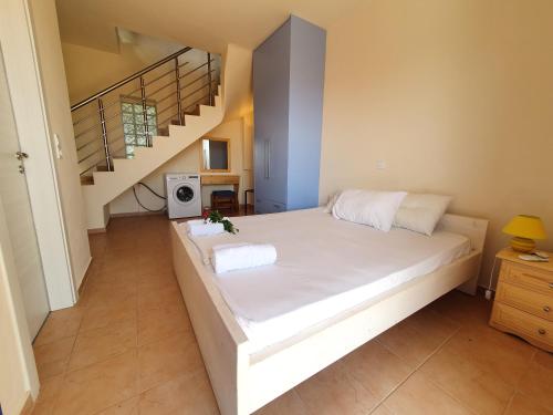 ein Schlafzimmer mit einem Bett mit weißer Bettwäsche und einer Treppe in der Unterkunft Stoupa Lefktro 3 in Stoupa