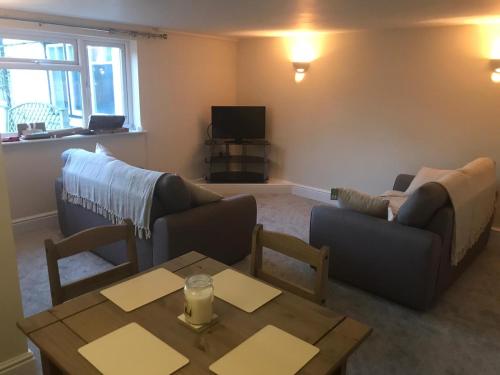 a living room with two couches and a table at 9 Bromleys Court in Church Stretton