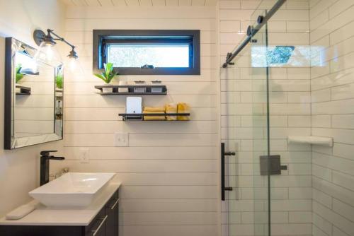 a bathroom with a sink and a glass shower at The Zephyr Modern Luxe Container Home in Bellmead
