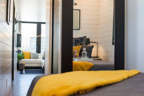 a bedroom with a yellow bed and a living room at The Zephyr Modern Luxe Container Home in Bellmead