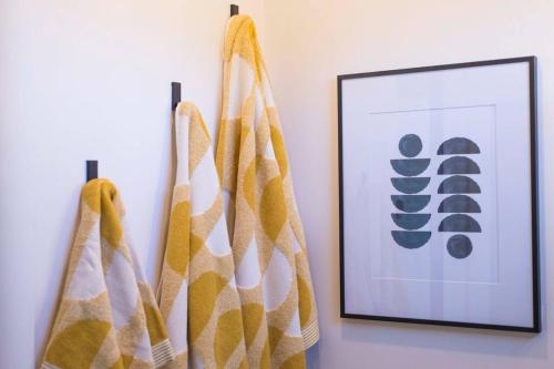 two towels hanging on a wall next to a picture at The Zephyr Modern Luxe Container Home in Bellmead
