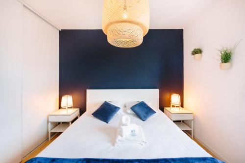 - une chambre avec un lit blanc aux murs bleus et 2 lampes dans l'établissement L'Idylle : T2 de standing avec parking - Gare/Cité des Congrès/Lieu Unique, à Nantes