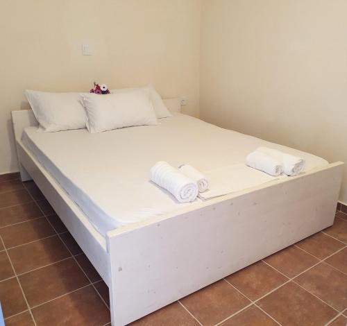 Una cama blanca con dos toallas encima. en Stoupa Lefktro 7, en Stoupa
