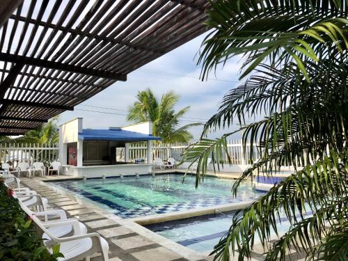 a swimming pool with chairs and a building at Blue Apartahotel in Coveñas