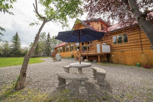 un tavolo da picnic con ombrellone di fronte a una cabina di Inn on the Lake - Whitehorse a Marsh Lake