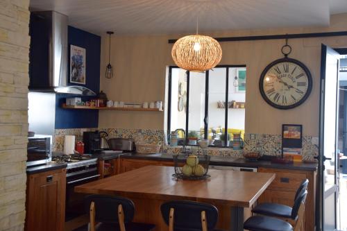 a kitchen with a table and a clock on the wall at Le Petit Patio in Aigues-Mortes