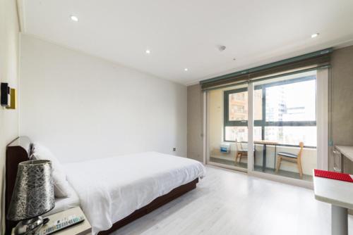a white bedroom with a bed and a large window at Residence Hotel Lamia in Daejeon