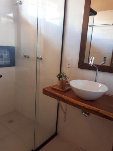 a bathroom with a sink and a shower with a mirror at Vila Gaia Guest House in Alto Paraíso de Goiás