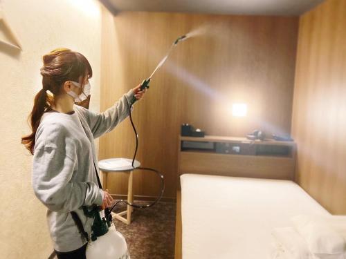 
a woman standing in a room with a blow dryer at Cabin House Yado Fujinomiya in Fujinomiya
