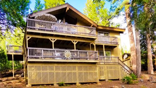 a large yellow house with balconies and trees at Cedar Ridge Retreat Lake Almanor in Lake Almanor