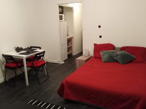 une chambre avec un lit rouge et une table avec des chaises dans l'établissement Appartement pres de beauval et des châteaux, à Montrichard