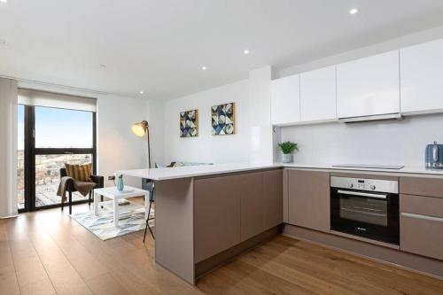 a kitchen with white cabinets and a counter top at One Bedroom Modern Apartment Next to Wembley Stadium! in London