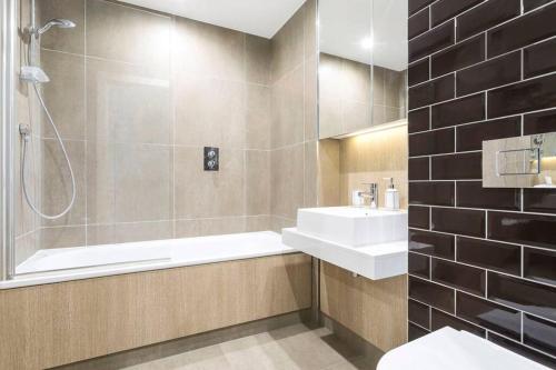 a bathroom with a tub and a sink and a shower at One Bedroom Modern Apartment Next to Wembley Stadium! in London