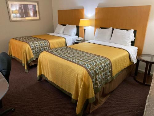 江克申市的住宿－Great Western Inn，酒店客房带两张带黄床单的床