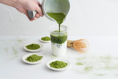 a person pouring a green drink into small white bowls at HOTEL 1899 TOKYO in Tokyo