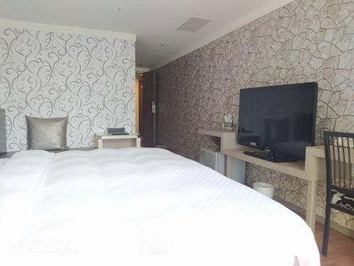 a bedroom with a bed and a flat screen tv at HengChang Business Hotel in Keelung