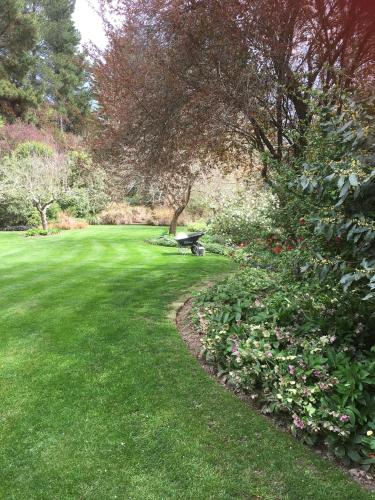 a park with a bench in the grass and flowers at Leader Valley Cottage - A Tranquil Retreat For Two in Mendip Hills