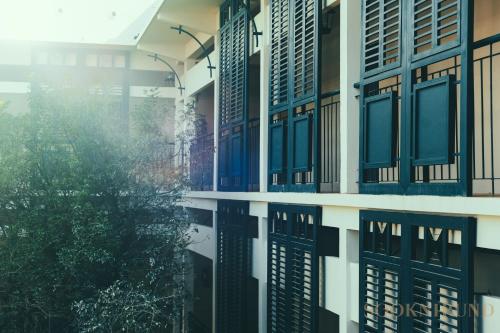 a building with windows and a tree in front of it at SOOKNIRUND HOTEL in Chiang Rai