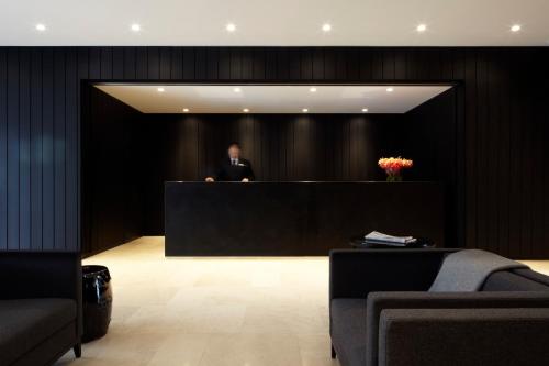 a man is standing behind a desk in a lobby at Burbury Hotel in Canberra