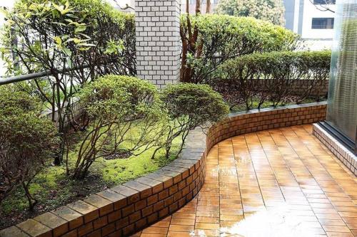 a courtyard with a brick wall and trees and bushes at THE TORII in Kumamoto