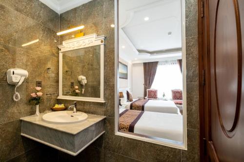 baño con lavabo, cama y espejo en Mai Vang Hotel, en Da Lat